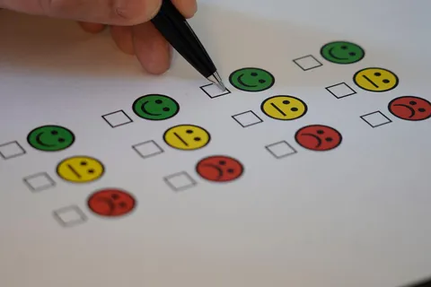 Iemand vult met een pen een enquête met smileys in
